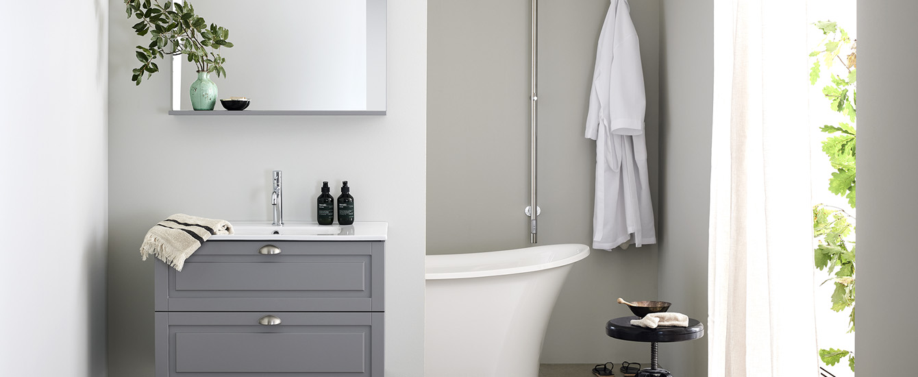 lantligt badrum med badrumsskåp i grått och badkar